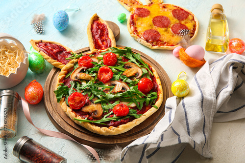 Composition with tasty pizzas and eggs for Easter celebration on blue background