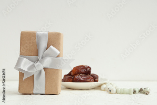 Gift box with dried dates and prayer beads for Ramadan on white table photo