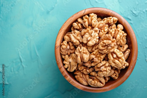 Close up of walnut halves in a wooden bowl on a colored background Promoting healthy eating and super foods