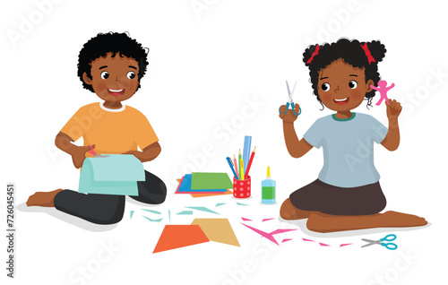 Cute little African kids cutting paper making art sitting on the floor together