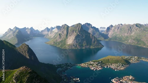 On a sunny day, an aerial view shows one of the best scenes one can see on a hike in Reinebringen, located in the Lofoten Islands of Norway. The mountains and island villages unfold below. photo