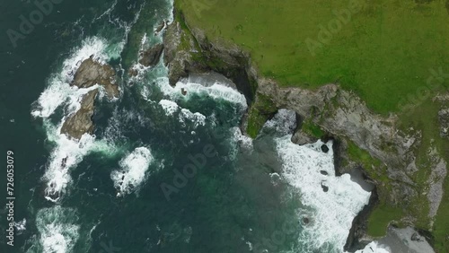 Aerial birdseyeview of waves crashing on a coastal cliff with bright green grass on the island of Achill in Ireland photo