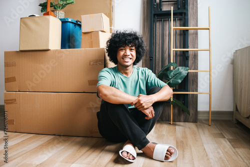 Tableau sur toile Cheerful young Asian male sitting on floor, looking at camera with happy face af