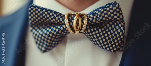 Man's bow tie adorned with gold wedding rings.