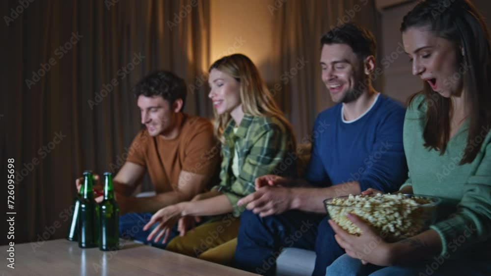Relaxed group sit couch preparing to watch movie together. People bringing beer Relaxed group sit couch preparing to watch movie together. People bringing beer