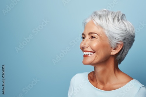 Portrait of a happy senior woman with a bright, confident smile on a blue background.
