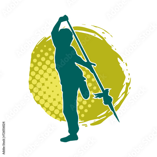 Silhouette of a wushu martial artist in action pose with a spear weapon. Silhouette of a fighter carrying a spear weapon.