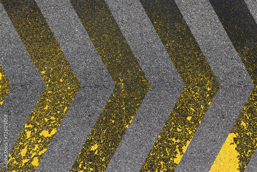 Chevrons jaunes sur asphalte, peinture dégradée sur route