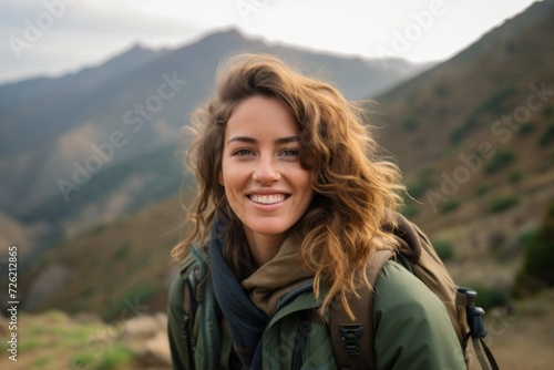 Portrait of a beautiful young woman with curly hair in the mountains