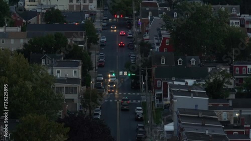 Dusk falls on a busy residential street lined with houses and traffic lights. Dark aerial view at night in USA city.
