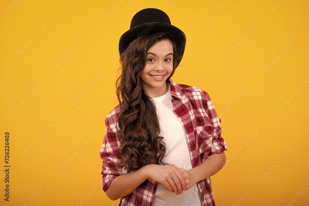 Child in magician hat, cylinder hat isolated on yellow background.