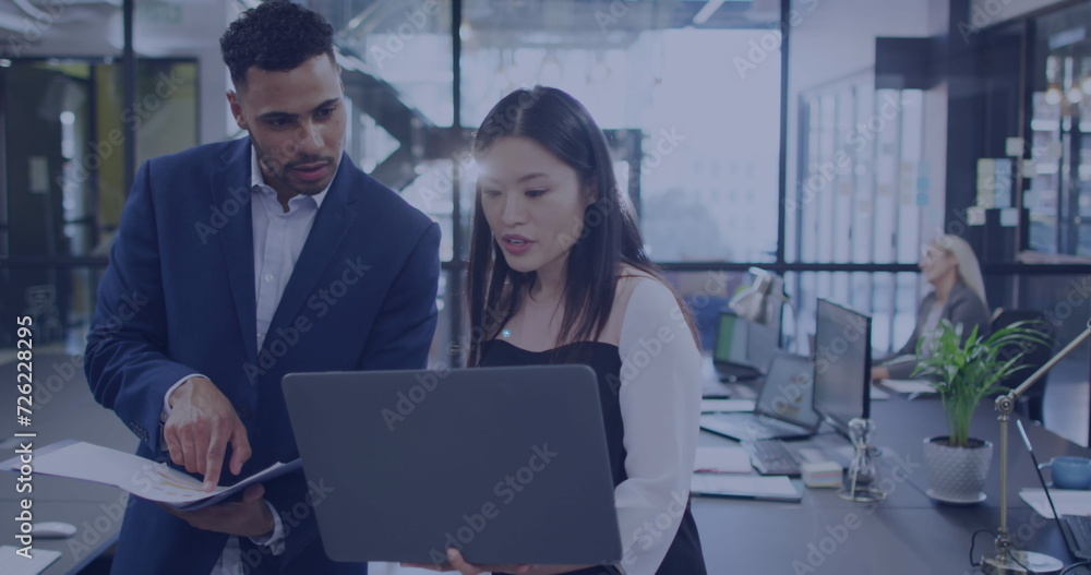 Naklejka premium Asian woman and young biracial man collaborate in a modern office