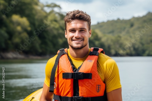 Portrait of a young man in a life jacket on a background of a mountain lake photo