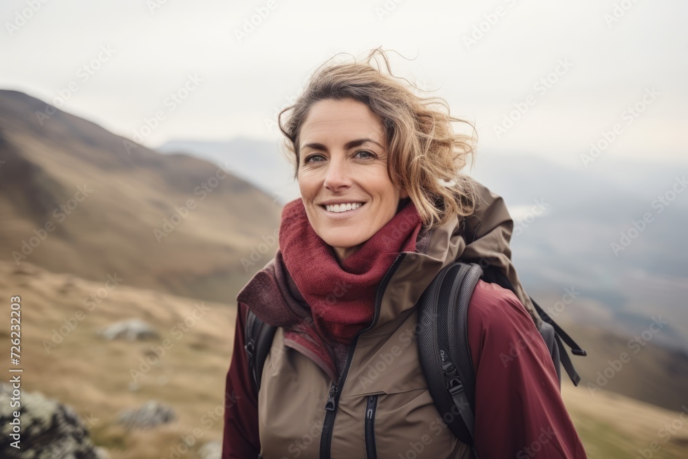 Portrait of a smiling woman with a backpack in the mountains.