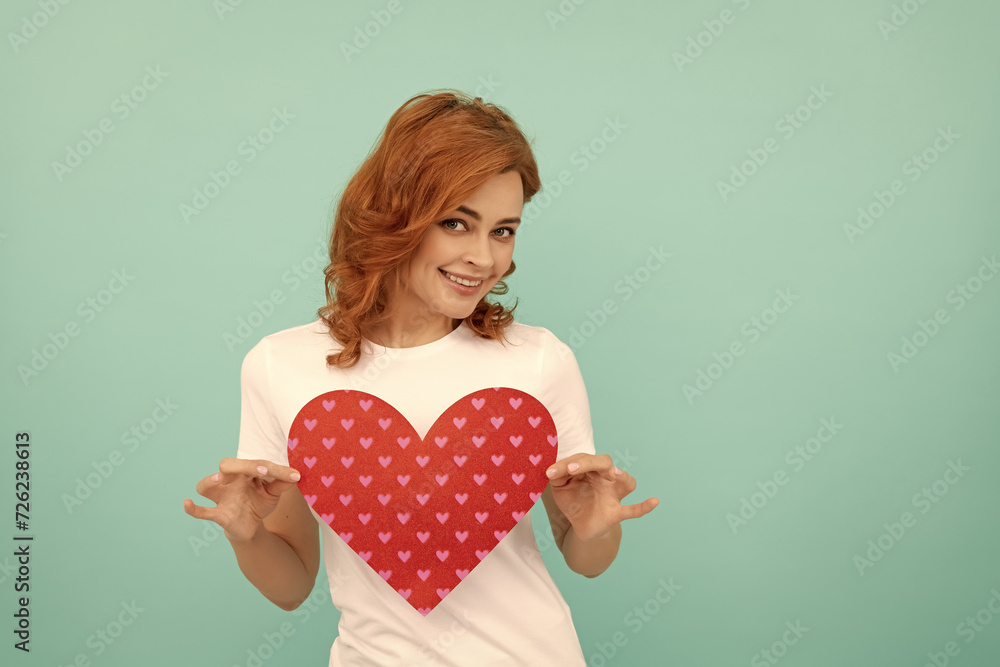 cheerful redhead girl hold red heart on blue background cheerful redhead girl hold red heart on blue background