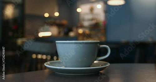 Close-up of a blue porcelain cup, atmosphere of a coffee shop in bokeh background, lifestyle horizontal video with copy space