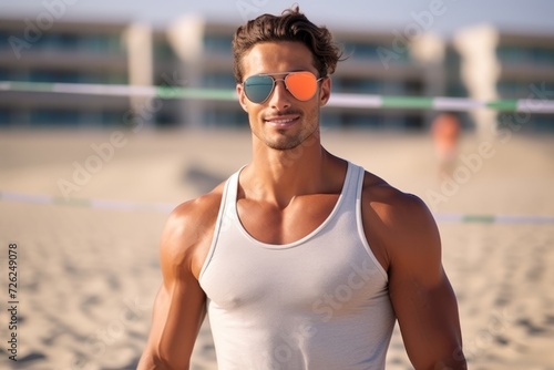 Portrait of a handsome young man at the beach wearing sunglasses.