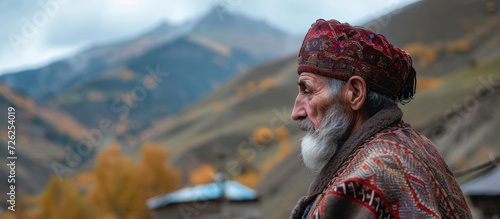 Man from local area dressed in traditional attire, standing in profile with Caucasian mountains as backdrop in Goor village. photo