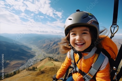 Portrait of happy little girl with helmet on the top of the mountain