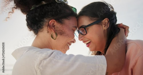 Love, hug and lesbian couple at a beach for summer, romance and bonding on date in nature. LGBTQ, support or gay people embrace sea with lens flare, trust and acceptance in Miami for travel adventure photo