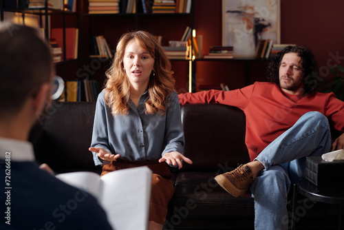 Over-the-shoulder of young Caucasian woman speaking about relationship problems during family therapy photo