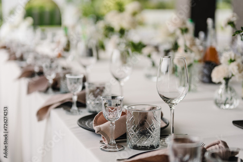 Serving, setting table in the backyard. Plate and glass, stack, wineglass, luxury rich decor. Wedding set up, dinner table reception on terrace. Birthday, baptism, event. Closeup details of interior.