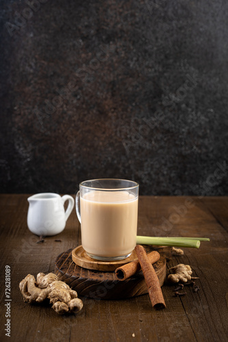 Hot ginger or wedang susu jahe milk with brown sugar, cinnamon, lemongrass and spice clove on wooden table.