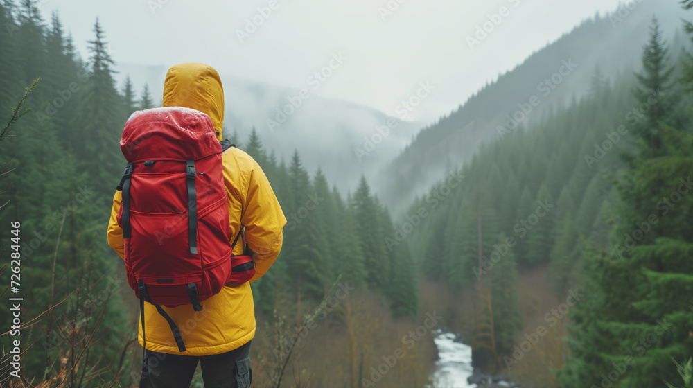 Traveler, adorned in a bright yellow jacket and carrying a red backpack, stands amidst the serene beauty of a misty forest.