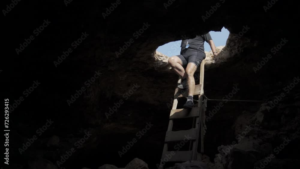 Man Descending into the Darkness of a Mysterious Cave Man Descending into the Darkness of a Mysterious Cave