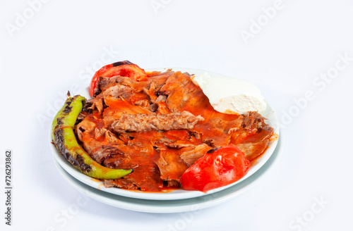 Top view of traditional Turkish cuisine food iskender kebab with melted butter, sauce, pita bread, tomato, pepper and yogurt isolated on white background.