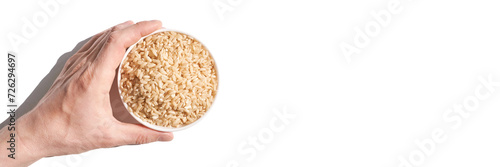 A bowl of uncooked brown rice, isolated against a white background. Healthy, savory dish includes whole grains like jasmine and basmati, showcasing a dieting Asian cuisine. Horizontal banner photo