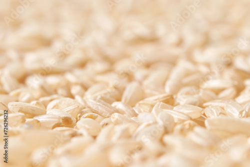 A background of dry brown rice grains showcases the integral, uncooked basmati texture. The macro view highlights the raw nature of this organic, whole food. photo