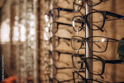 Eyeglasses shop. Stand with glasses in the store of optics. Woman s hand chooses glasses.