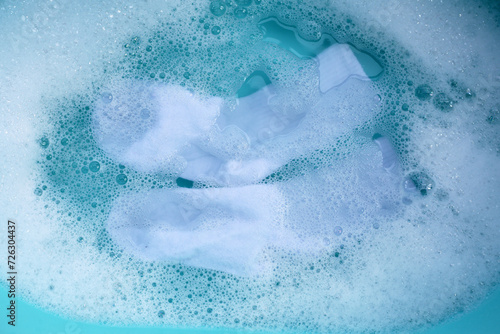 Dirty socks soaked in water, dissolving detergent in basin. photo