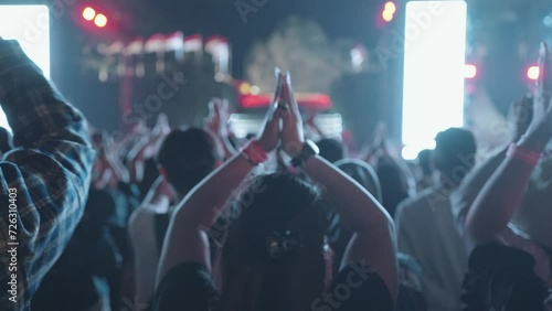 Unrecognizable People Crowd Dance and Hands Up at Evening Live Music Concert on Stage at Festival with Laser and Light in Slow Motion photo