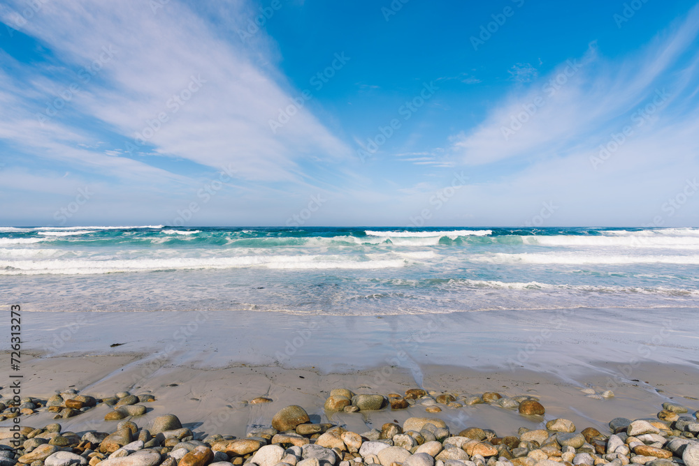 Ocean beach with large stones and sand under a blue sky and clouds Ocean beach with large stones and sand under a blue sky and clouds