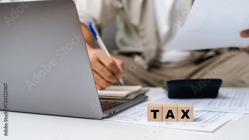 Man is calculating annual tax, monthly expenses with calculator and filling form of Individual Income Tax Return. Season to pay Tax and Budget planning concept.