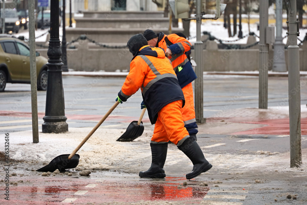 Workers with shovels cleaning road, snow and melting ice removal in winter city Workers with shovels cleaning road, snow and melting ice removal in winter city