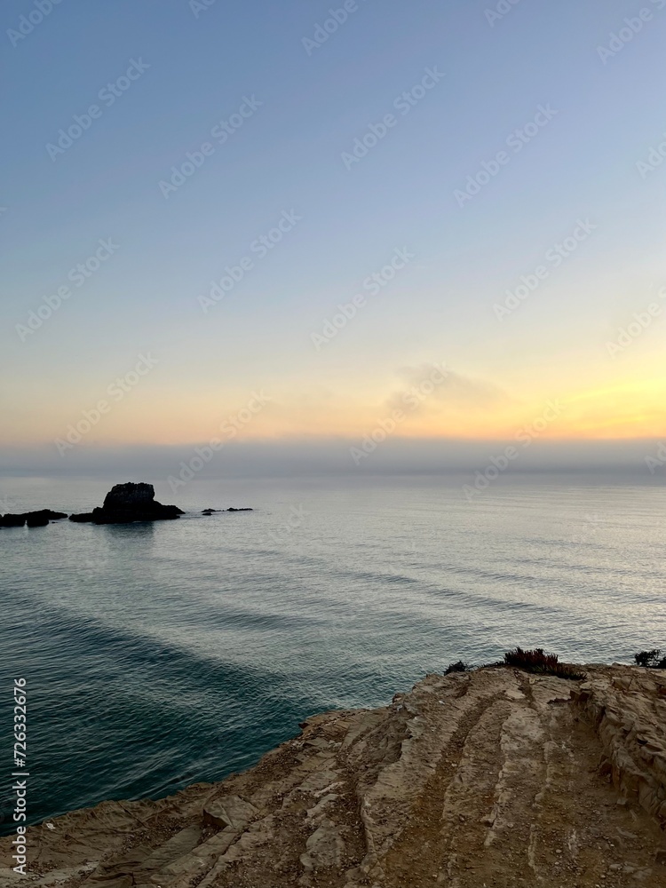 Orange sea horizon, rocky coast, evening seascape background