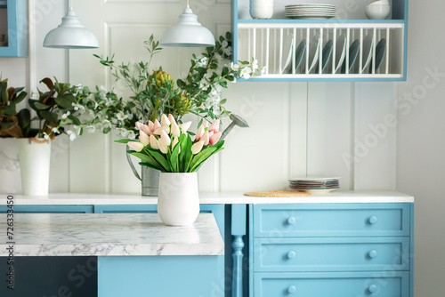 Wallpaper Mural Kitchen island in dining room. Stylish cozy cuisine with tulips flowers in vase. Wooden kitchen in spring decor. Kitchen utensil, dishes and plate on shelves. Blue kitchen interior with furniture	
 Torontodigital.ca