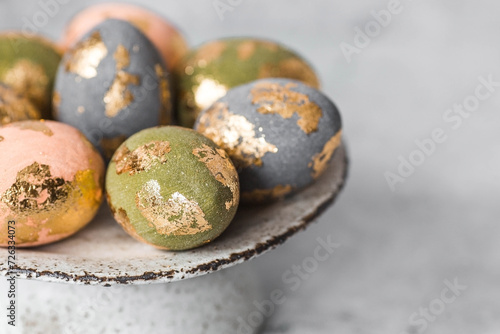 Beautiful Easter eggs with a golden coating were laid on a steel concrete plate on a gray background. The concept of happy Easter 2024.