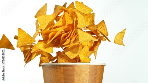 Flying Fried Tortilla Chips Exploding from Paper Bucket. Concept of Flying Junk Food.