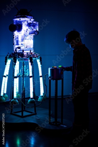 Silhouette of a young boy playing with the huge light robot