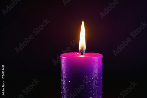  Purple candle burning with streaks of paraffin on dark background
