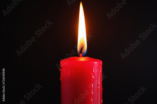 Red candle burning with streaks of paraffin on dark background