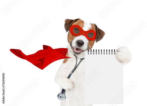 jack russell terrier wearing like a doctor with superhero cape and with stethoscope on his neck looks at camera and shows empty notepad. Isolated on white background