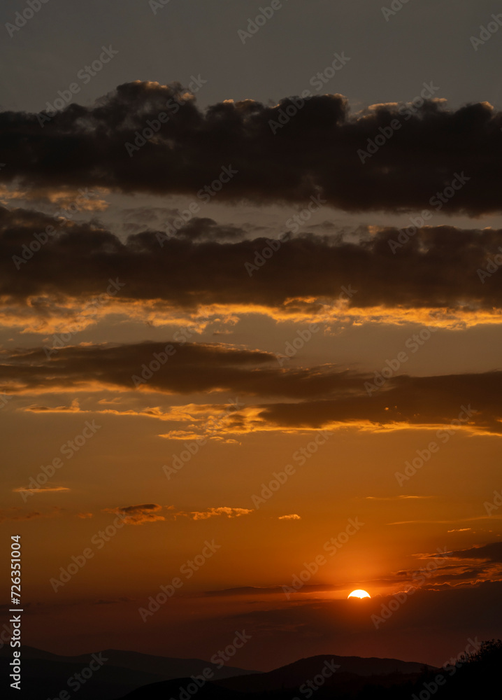 Beautiful sunset in the mountains. Sunset View from the Top of a Mountain. Sunset in strong orange tones in Serbia. The sun falls for horizon, a sunset. Shadows are condensed, beautiful clouds. 