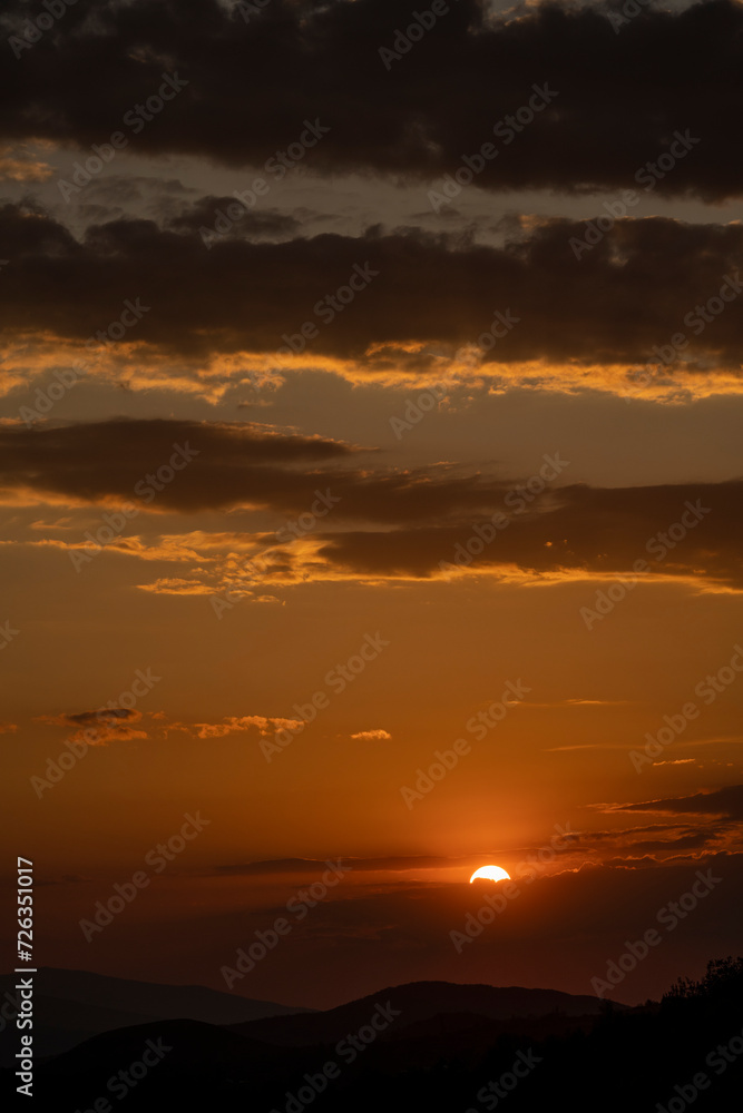 Beautiful sunset in the mountains. Sunset View from the Top of a Mountain. Sunset in strong orange tones in Serbia. The sun falls for horizon, a sunset. Shadows are condensed, beautiful clouds. 