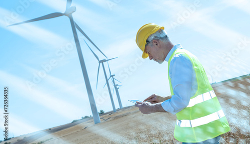 Engineer using digital tablet for wind turbine inspection; light effect