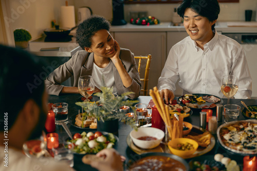 Group of smiling friends enjoying in conversation during Christmas party at home